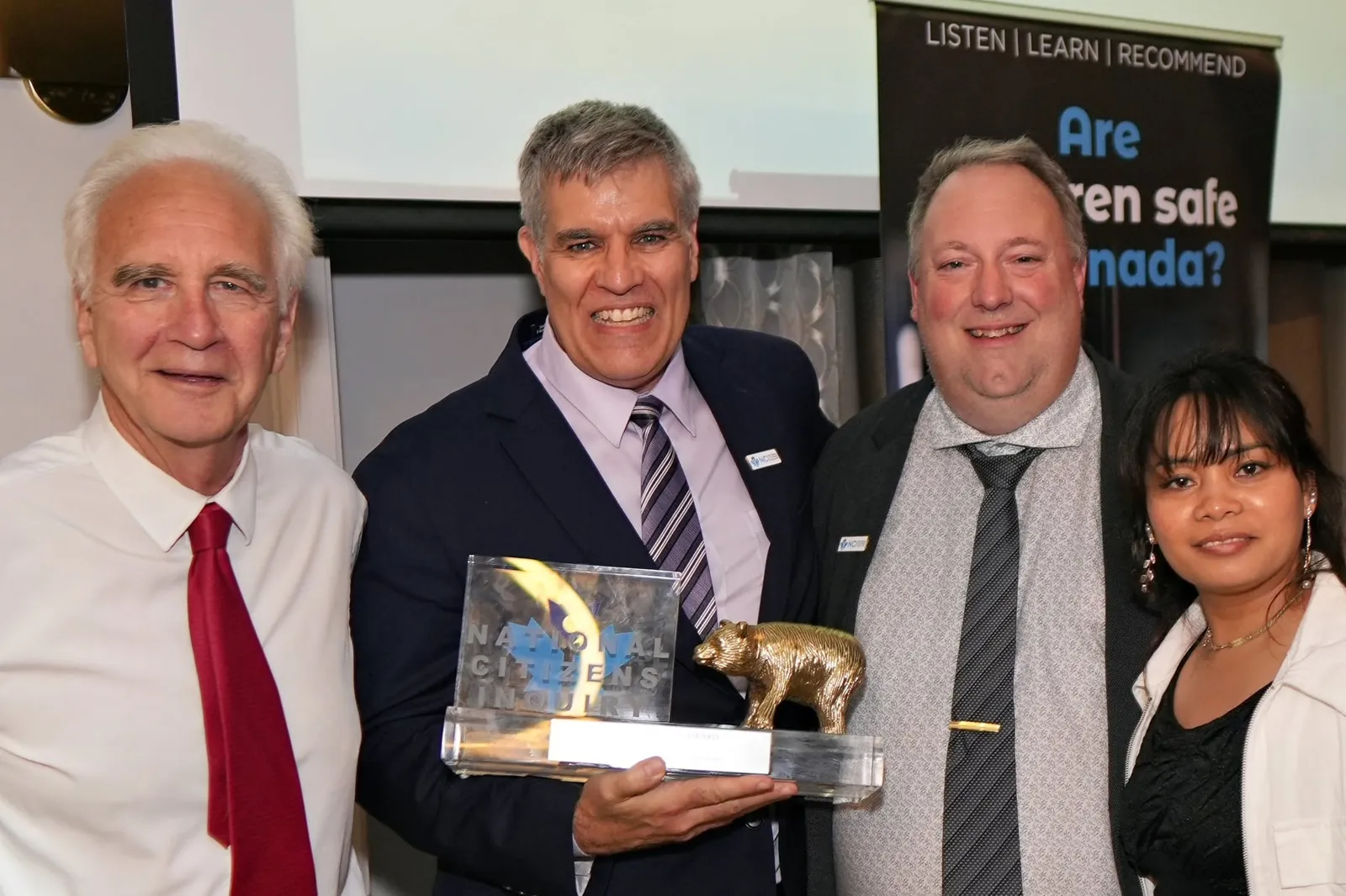 Four people with a National Citizens Inquiry award